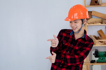 Lovely Asian carpenter boy acting present his work in front of DIY woodworking table carpentry shop with copy space