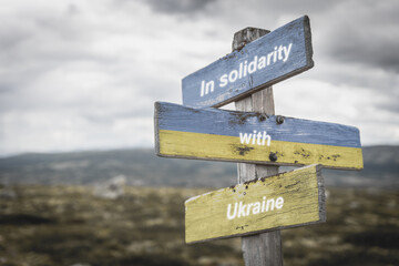 in solidarity with ukraine text on wooden signpost with the ukranian flag painted on it. Peace and war concept.
