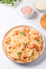Italian pasta fettuccine or spaghetti in a creamy cheese sauce with shrimp or prawns on a plate