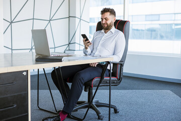 Portrait of a business young successful man in a modern office sitting at a table