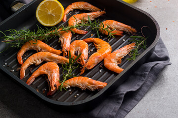 Shrimps on stone background. Grilled prawns with rosemary and lemon. 