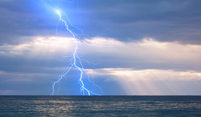 Beautiful landscape with lightning over the calm sea at sunset 