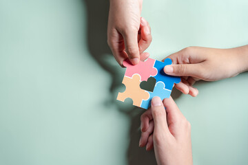 Color puzzle symbol of awareness for autism spectrum disorder family support. Father, Mother, Children holding jigsaw puzzle Autism World Awareness Day.
