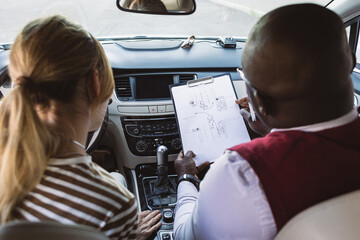Driving school concept. A car instructor teaches a young woman how to drive. Teaching the rules of...