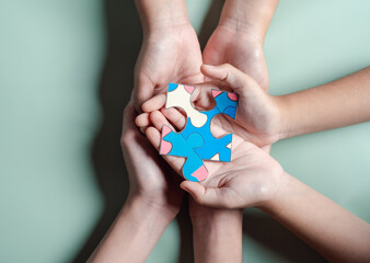 Color puzzle symbol of awareness for autism spectrum disorder family support. Father, Mother, Children holding jigsaw puzzle Autism World Awareness Day.