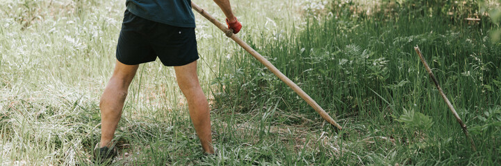 mowing the grass traditional old-fashioned way with the hand scythe on the household village farm....