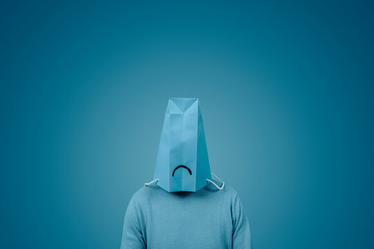 man wears a blue bag with a sad face in his head