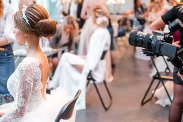 Competition among bridal hair stylists. Videographer shoots a model in a wedding dress, with hair...