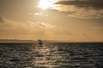 windsurfer at Hill Head Hampshire England with the Isle of Wight and an orange haze from the sun setting in the background
