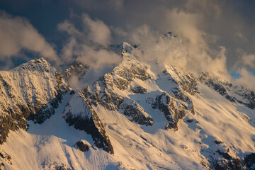 Majestic mountains scene with snow capped peaks in the clouds during sunset, Italian Alps, Passo del Tonale, Lombardy, Italy.