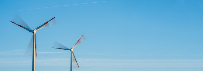 Moving wind turbines in front of a blue sky panorama