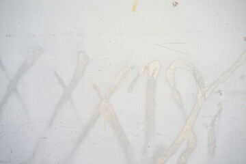 White spray painted on the dirty cement wall texture background.