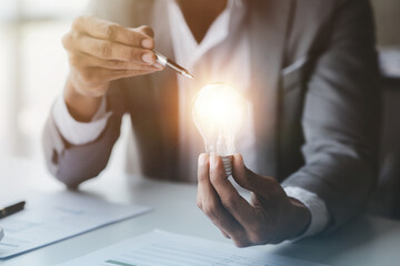 Person holding glowing lamp, Creative new idea. Innovation, brainstorming, strategizing to make the business grow and be profitable. Concept execution, strategy planning and profit management.