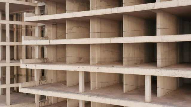 Building under construction - reinforced concrete high-rise multistory tower block development. Geometric grid-like pattern of walls and slabs in a housing project. Civil engineering and architecture.