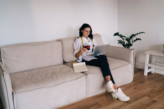 Young female tailor browsing netbook while working on design project