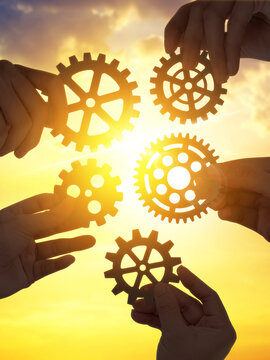 Five hands holding gear from of the puzzles at sunset . Concept of teamwork business idea.