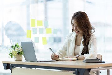 Obraz premium Charming Asian businesswoman working on a laptop in the office.
