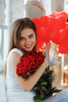 Fashion interior photo of beautiful smiling woman with dark hair holding a big bouquet of red roses in Valentine's day.