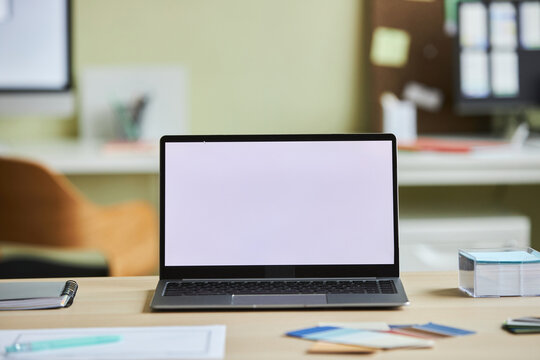 Background image of open laptop with white screen mock up on desk in cozy office setting, copy space