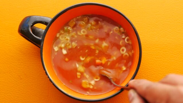 spoon stirring instant cup soup in a mug on table 