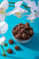Handmade rustic chocolate truffles with white orchid flowers on turquoise