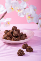 Handmade rustic chocolate truffles with white orchid flowers on pink