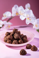 Handmade rustic chocolate truffles with white orchid flowers on pink