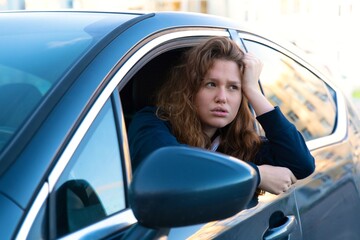 Portrait of sad unhappy girl, young angry upset frustrated woman driver is sitting in her car, new...