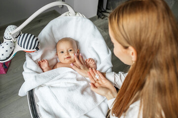 Mother applies moisturizer for healthy skin care on cute baby face. Skin care lotion for children.