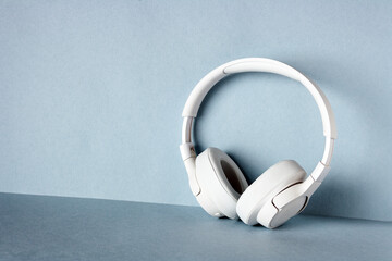 white headphones stand against the wall, on a blue background, copy space