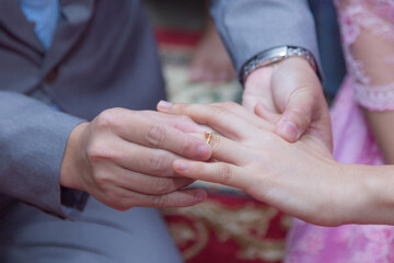 the  groom  is putting an engagement diamond wedding ring on the bride finger. newlyweds with rings on fingers