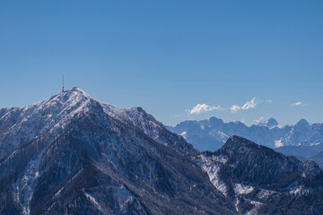 Scenic view of snow capped mountain peak Dobratsch, Julian Alps and the Karawanks (Karawanken) seen from Kobesnock in Bad Bleiberg, Carinthia, Austria, Europe. Winter wonderland landscape on sunny day