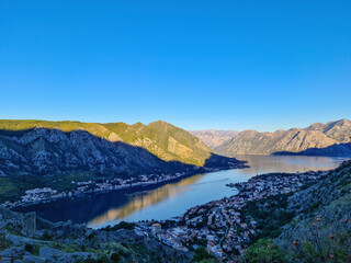 Fototapeta premium Panoramic view of the bay of Kotor during sunrise in summer, Adriatic Mediterranean Sea, Montenegro, Balkan Peninsula, Europe. Fjord winding along the coastal towns. Lovcen and Orjen mountain range