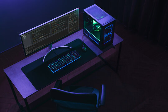 Top view of home coder workspace with professional programming setup. Empty IT specialist studio in neon light. Copy space. 