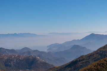 Obraz premium Panoramic view of dramatic karst mountain chains Dinaric Alps surrounding the Lake Skadar National Park seen from Goli Vrh, Montenegro, Balkan, Europe. Valley is covered by mystical fog, blue hills