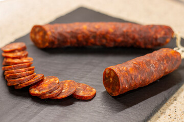 Authentic chorizo ​​from León cut into thin slices, presented on a slate stone, made with different Iberian pork meats