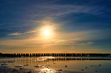 Groynes jut into the sea at sunset. The sun shines on the Baltic Sea. Landscape