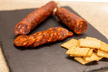 Authentic chorizo ​​from León cut into thin slices, presented on a slate stone, made with different Iberian pork meats