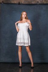 Full body portrait of a young beautiful blonde model in white dress