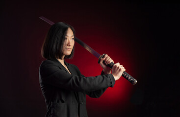 portrait of an Asian girl with a katana in her hands posing emotionally on a black background copy paste