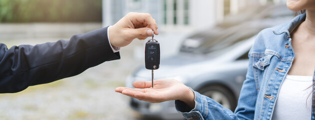 transportation rental automotive business concept. Close up hands of rental auto agent giving car remote key to client to travel sightseeing.