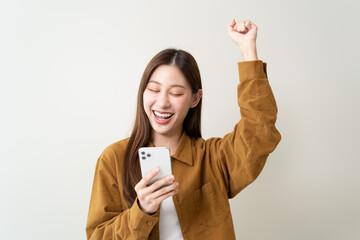 Happy Asian woman holding a smartphone and winning the prize.