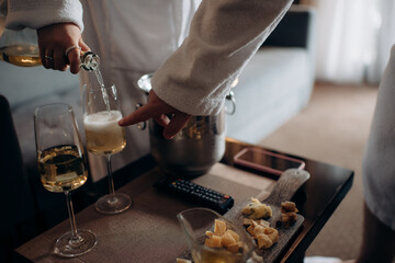 waiter pouring wine into a glass with a bottle of champagne