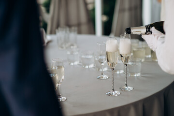 waiter pouring wine into a glass with a bottle of champagne