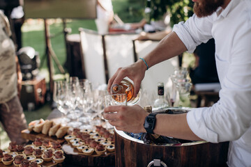 waiter pouring wine into a glass with a bottle of champagne