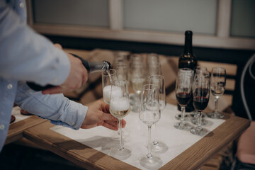 waiter pouring wine into a glass with a bottle of champagne