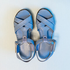 Blue sandals on light background. Stylish summer women's leather shoes, top view