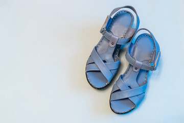 Blue sandals on light background. Stylish summer women's leather shoes, top view, copy space