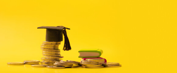 Graduated cap with coins on yellow background. Savings for education concept