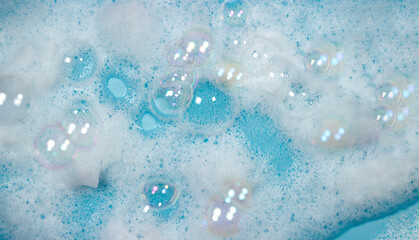 Soap foam on the water on a blue background. Foam texture as background for image. Soap bubbles on the background of foam